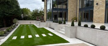 Landscaped hillside garden with terraced patios, lush lawn, and porcelain paving